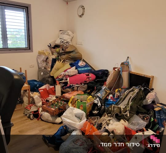 חדר מבולגן עם ערימות של בגדים, נעליים וצעצועים